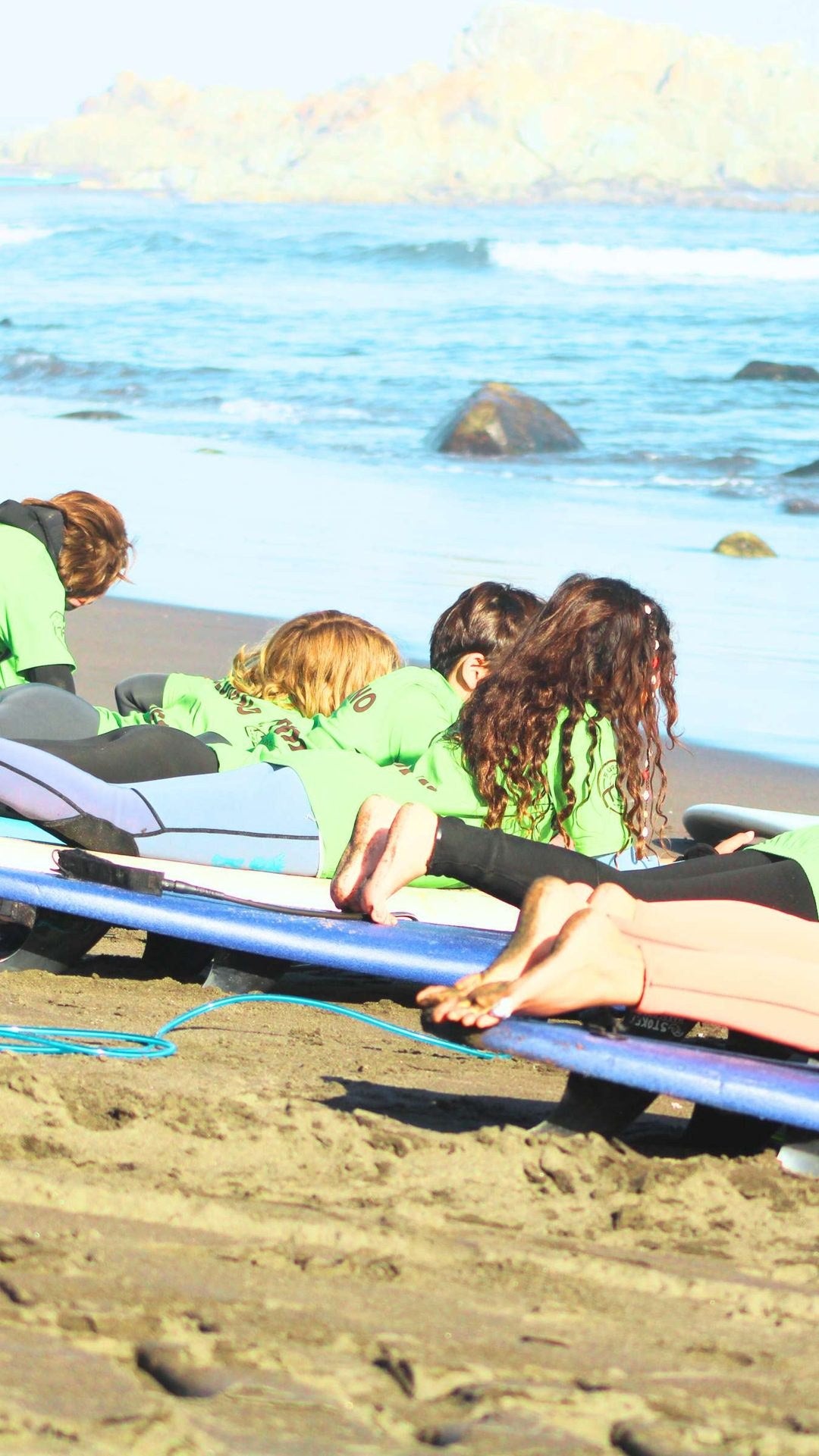 Niños practicando técnica de surf en la arena